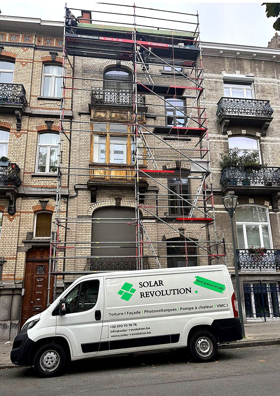 Chantier de rénovation de façade en cours, échafaudage et camion Solar Revolution