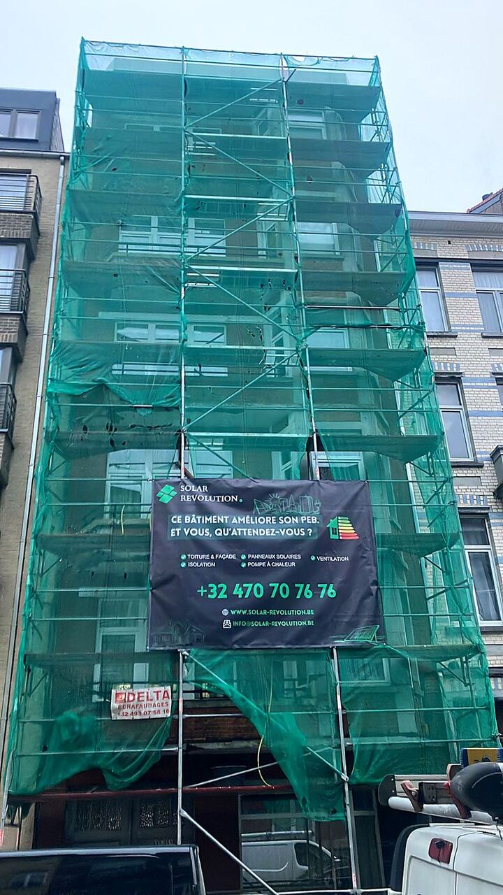 Échafaudage bâché pendant une rénovation de façade, banderole Solar Revolution